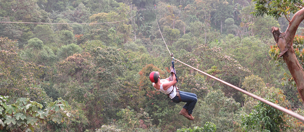 Former patient zip lines through the forest canopy