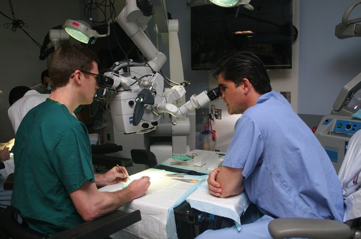 In the Surgical Innovations Lab, Dr. Christopher Winfree (right) guides a resident through microsurgical techniques